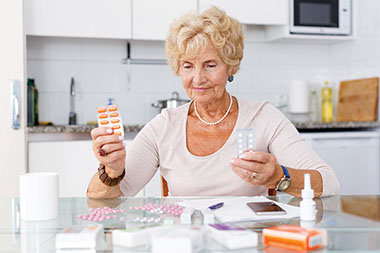 Women sitting at kitchen table organizing medication.