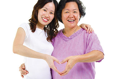 Image of mother and daughter making a heart with their hands.
