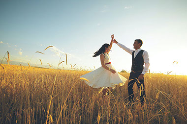 Couple dancing in open wheat field.