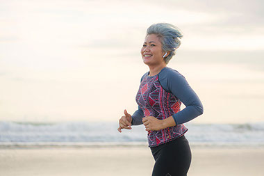 Middle aged women jogging on beach.