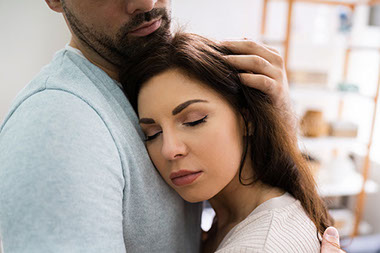Close up of women's face as she leans on man chest for support.