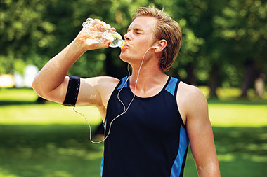 Man outside drinking water and exercising.