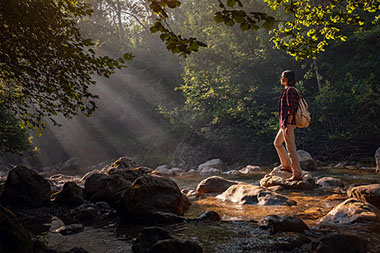 Women standing on rock in middle of a creek.