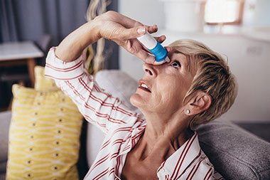 Older women using eye drops.