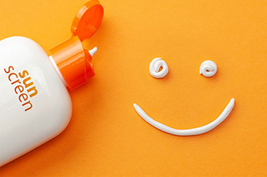 Open bottle of sun screen with lotion making smiling face. Open bottle of sun screen with lotion making smiling face.
