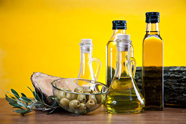 Image of oilve oil and green olives in a clear bowl.