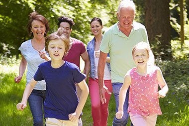 Image of generational famiy running and walking at the park.