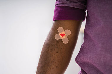 Arm with bandaid and heart where he gave blood.