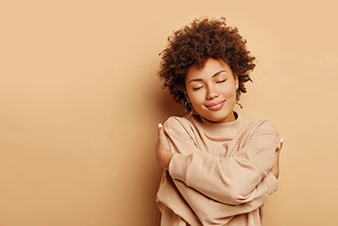 Female smiling while hugging herself.