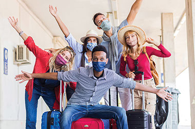 Group of friends with luggage, wearing face masks, ready to travel.