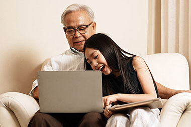 Granddaughter helping grandfather on the computer.
