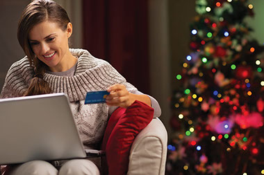 Image of female on laptop with credit card in hand.