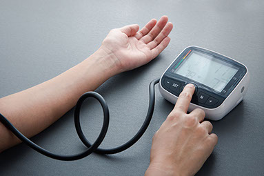 Close up of arm and hand using an at home blood pressure machine.