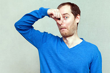 Image of man plugging his nose with hand.