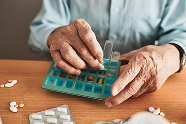 Close up of hands filling a medication pill holder. Close up of hands filling a medication pill holder.