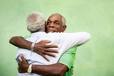 Image of 2 elderly male friends hugging.