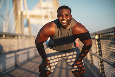 Smiling man outside exercising.