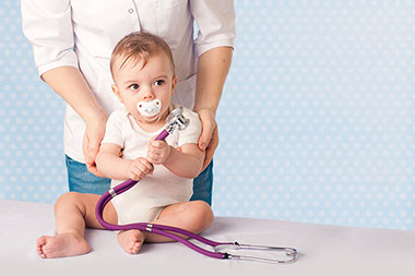 Image of parent holding baby on doctor's table.