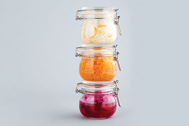 Three stacked jars with picked carrots, beets and onion.