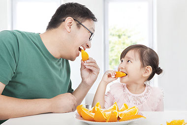 Image of father and daughter eating oranges.