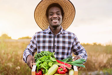 Man holding a basket of vegetables that he harvested.