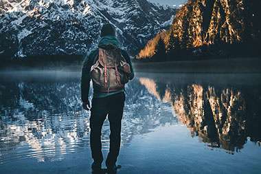 Man standing in front of lake and mountains. Man standing in front of lake and mountains.