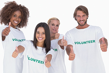 Benefits of volunterring. Image of 4 volunteers smiling with thumbs up.
