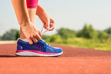 Image of person lacing tennis shoe.