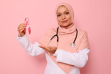 Female doctor holding a pink ribbon for breast cancer awareness.