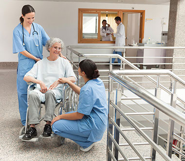 Image of women in wheel chair talking with two nurses.