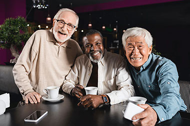 Three older men having coffee together.