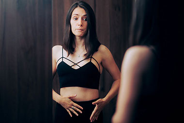Women looking at her body in a mirror.