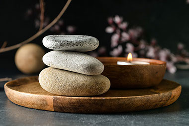 Wooden tray with stacked rocks and a candle.