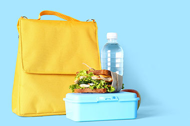 Sandwich and water bottle sitting next to lunch bag. Sandwich and water bottle sitting next to lunch bag.