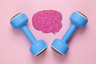 A pink paper brain with 2 dumb bells next to it.