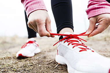 Image of person lacing up shoes.