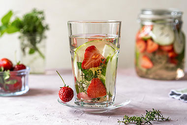 Glass of water flavored with strawberries and cucumbers.
