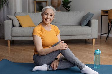 Smiling women sitting on a yoga mat.