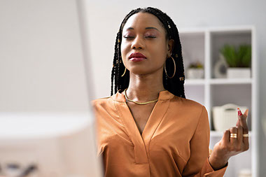 Women sitting at desk, meditating.