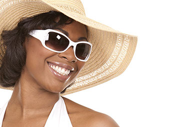 Look cool and protect your eyes. Image of women smiling while wearing sunglasses and a sun hat.