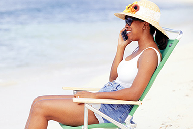 Image of women sitting at the beach talking on the phone.