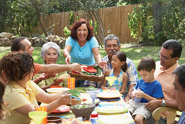 Image of multi-generational family having dinner in the back yard.