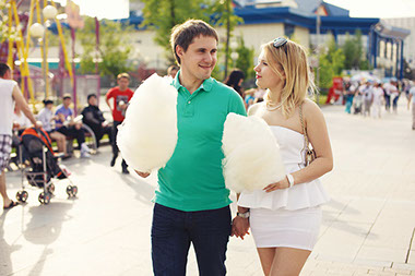 Walking off the midway munchies. Image of couple walking at a state fair with cotton candy.