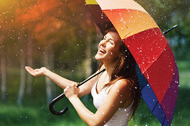 Happy women holding colorful umberalla in the rain.