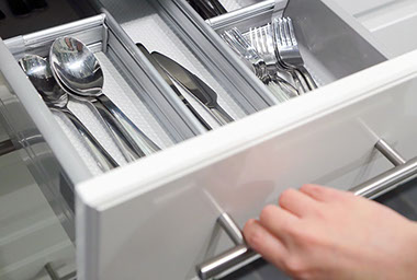 Image of open kitchen drawer with spoons, knives and forks.
