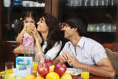 Home-cooked meals promote family togetherness. Image of young family sitting around the table eating together.