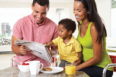 Image of family enjoying breakfast and the morning paper.