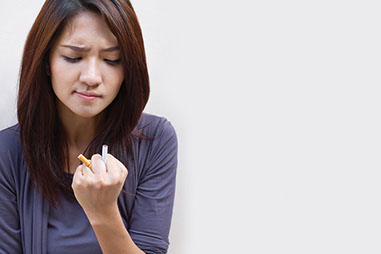 Image of young women crushing a cigarette in her hand.