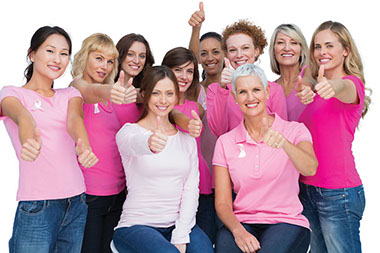 Image of a group of women wearing pink shirts, smiling with thumbs up.