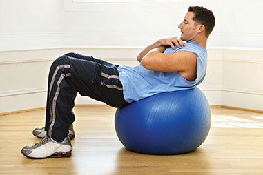Will ab exercises shrink your belly? Image of man using a fitness ball to do ab exercises.